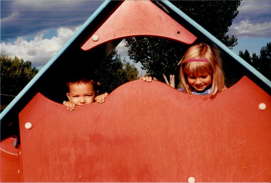 Brandon and a childhood friend peeking through playground equipment